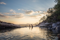 Couple swimming in Gunlom top pools at sunset